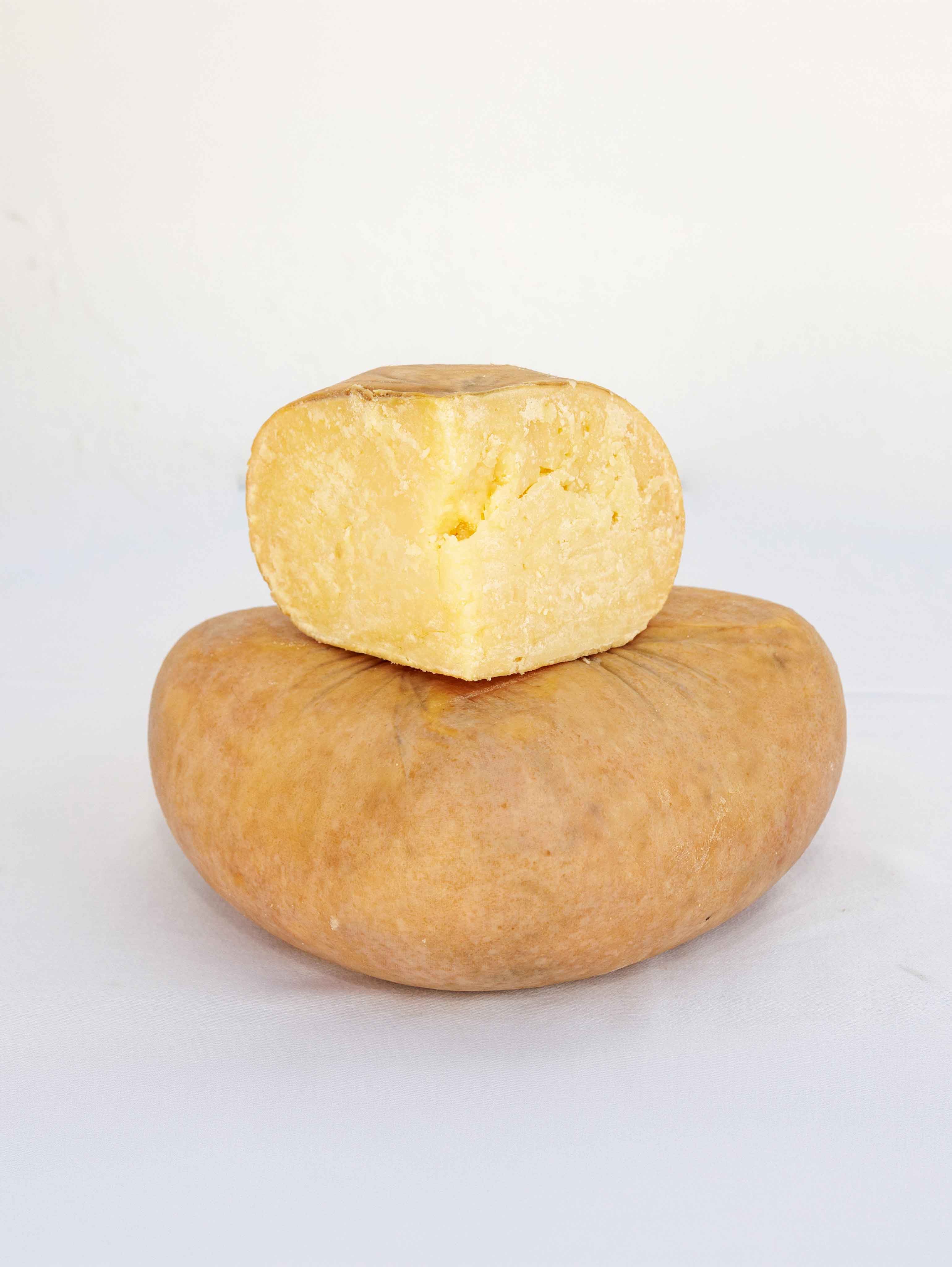 Queso curado entero con porción cortada